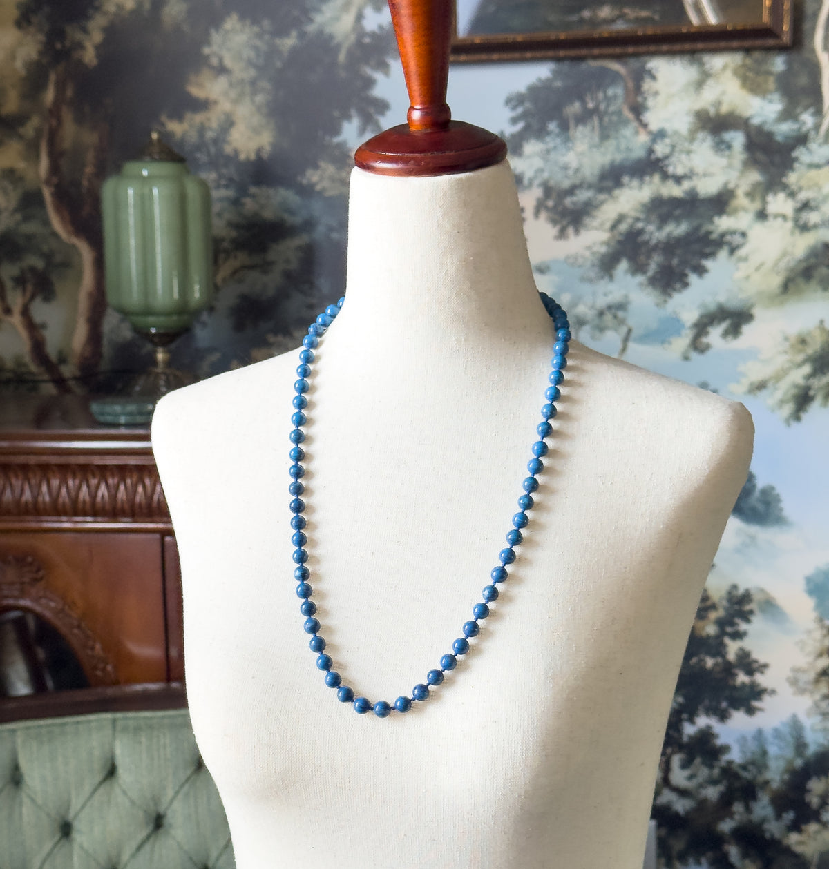 Almost the same view with slightly different angle, framed closer on the dress form so the small knots spacing each round bead along the strand can be made out.