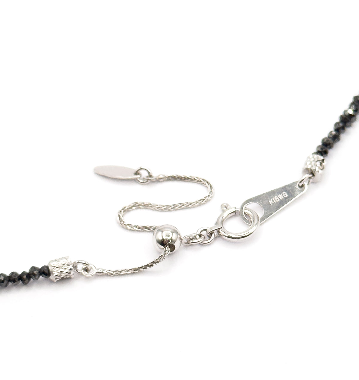 The adjustable extension chain seen from above, a small round slider bead running along it to a flat oval end tag, with the spring ring and stamped tag alongside the beaded strand.