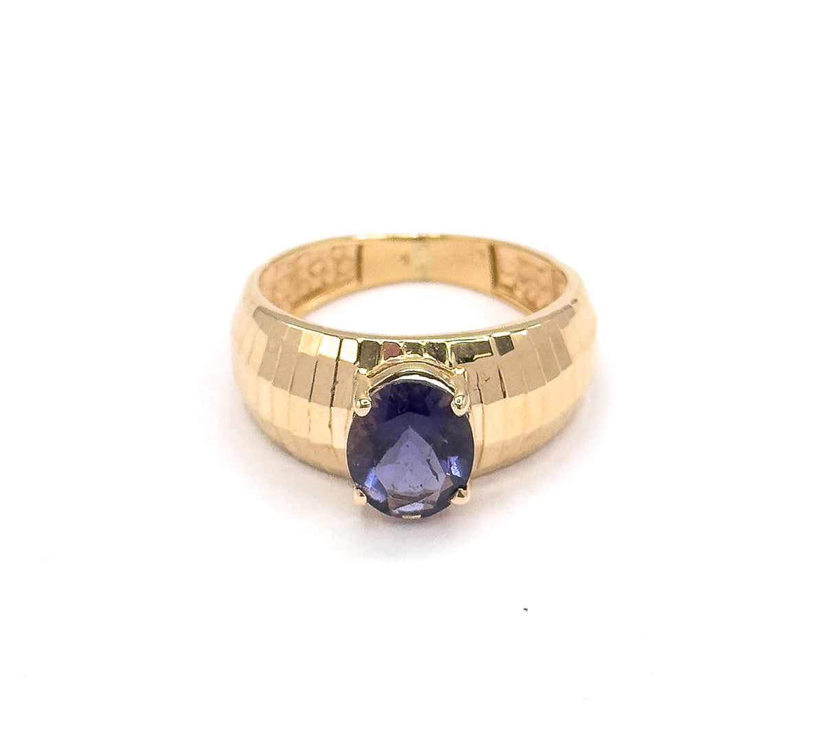 Viewed slightly from above the front, the oval iolite sits low on the wide band while the ring's open back shows through the top, the grooved yellow gold catching light across both shoulders.