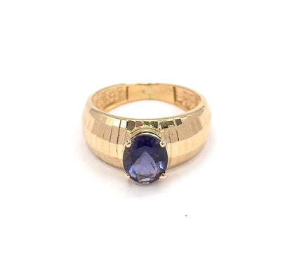 Viewed slightly from above the front, the oval iolite sits low on the wide band while the ring's open back shows through the top, the grooved yellow gold catching light across both shoulders.