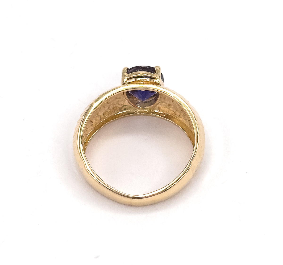 Looking straight through the finger opening from behind, the open gallery reveals the underside of the oval iolite above the tapering shank, with the dimpled inner band framing the view.