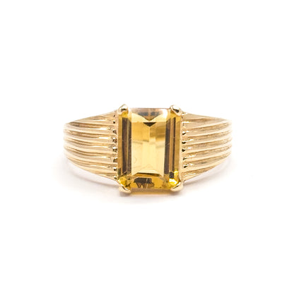 A final straight-on view of the whole ring tipped slightly forward, so the citrine's golden table and upper steps show together with the full fan of ribbed shoulder lines on both sides.