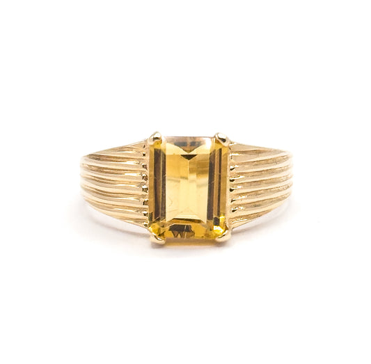 A final straight-on view of the whole ring tipped slightly forward, so the citrine's golden table and upper steps show together with the full fan of ribbed shoulder lines on both sides.