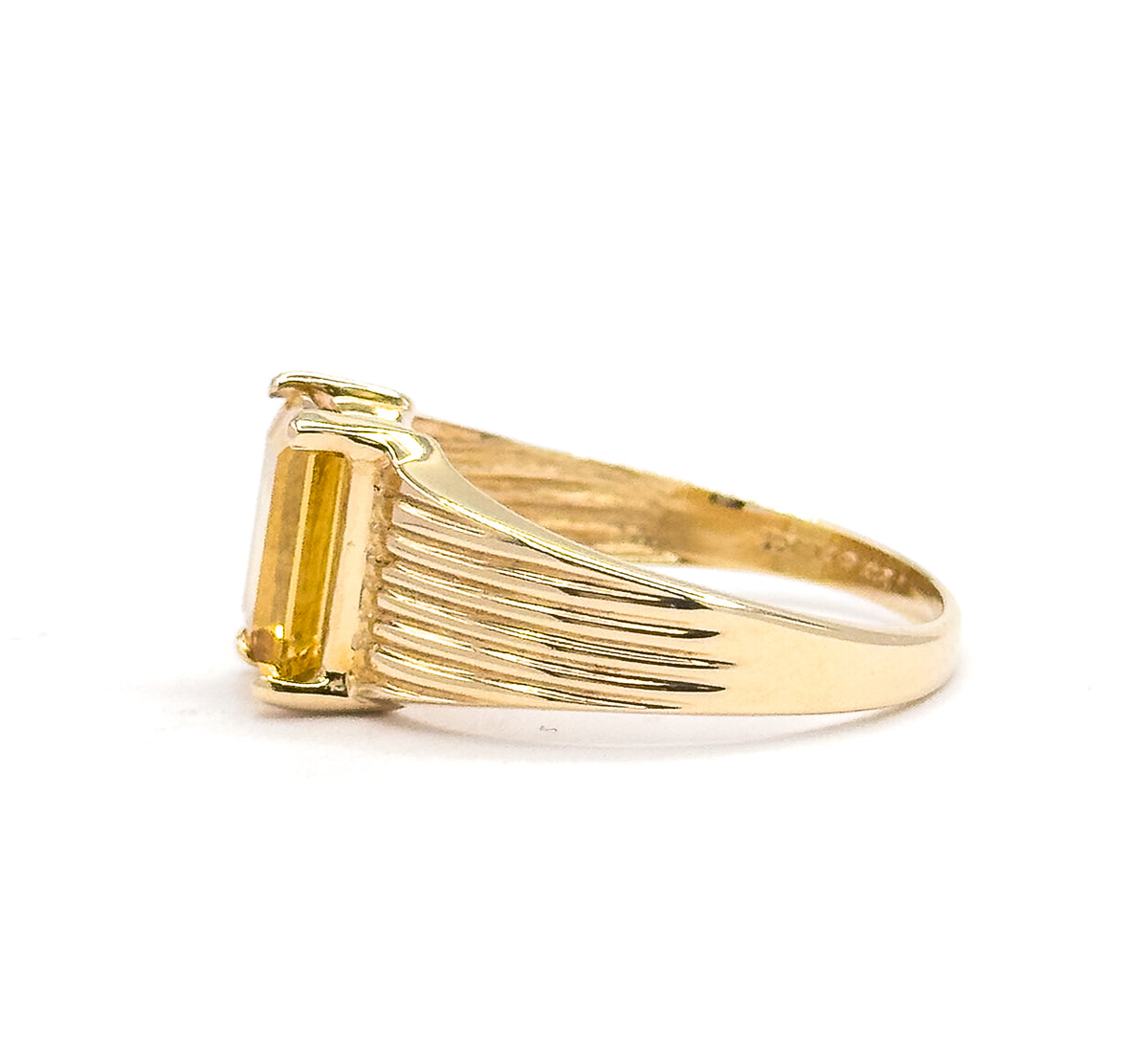 A straight side-on view from the opposite direction, the citrine's long rectangular side held by prongs at the face while the ribbed lines fan back along the shoulder into the smooth tapering shank.
