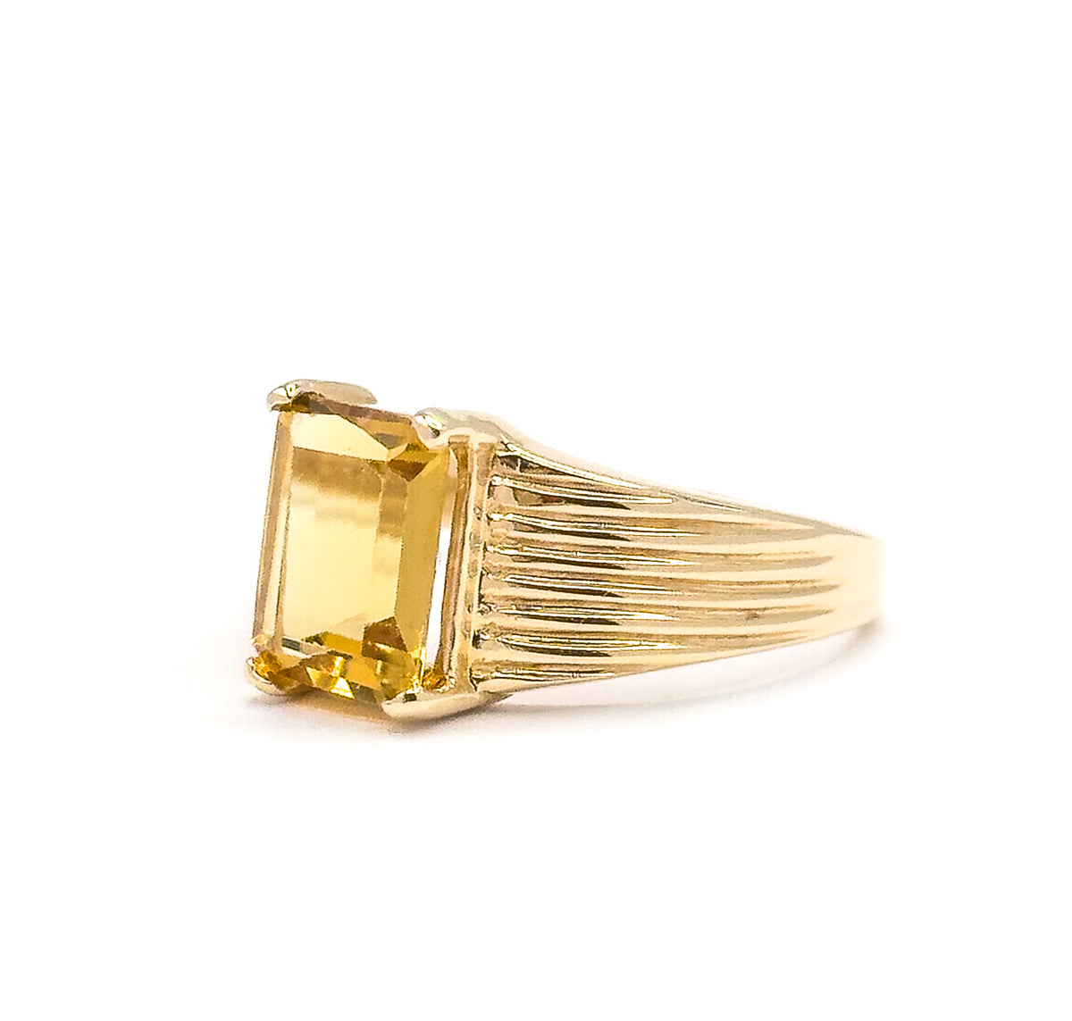 A closer side angle off the hand, the ribbed grooves of the shoulder filling the frame while the citrine's stepped facets catch light at the prong-held corners above the tapering shank.