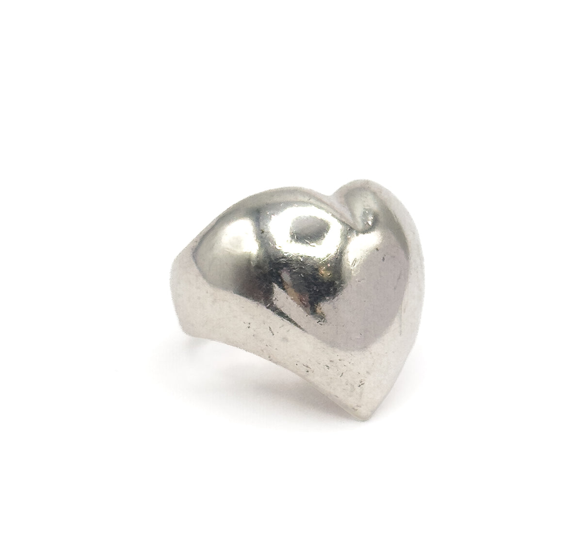 Off the hand now against a plain white background, the ring stands upright so the full domed heart face and the narrow shank curving beneath it are visible.