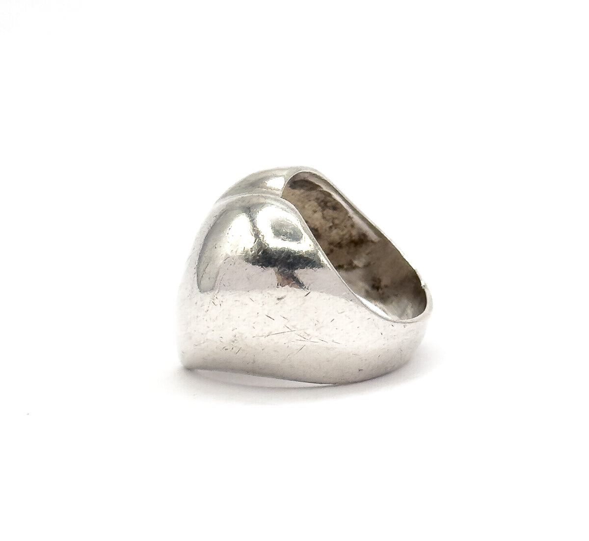 Angled from the side, the heart's domed profile rises and swells away from the broad lower shank, with the open band mouth and shadowed interior visible behind it.