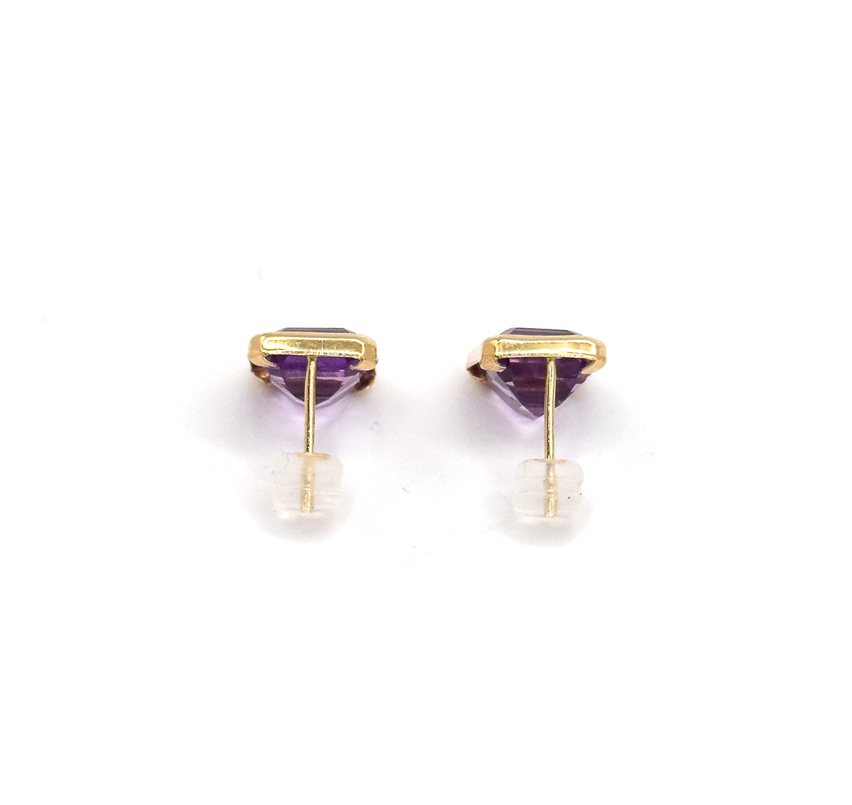 Both studs side by side from behind, the yellow gold bezels seen edge-on with the pointed purple stones below and each post threaded through a clear backing.