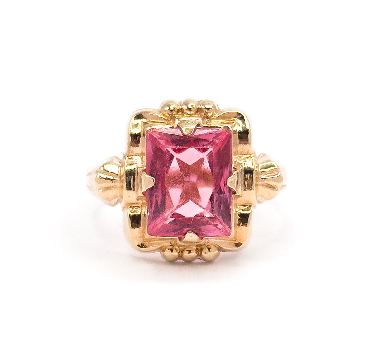 Almost the same view with slightly different angle, cropped closer so the small claws gripping the top and bottom edges of the pink glass and the fluted yellow gold shoulders fill the frame.