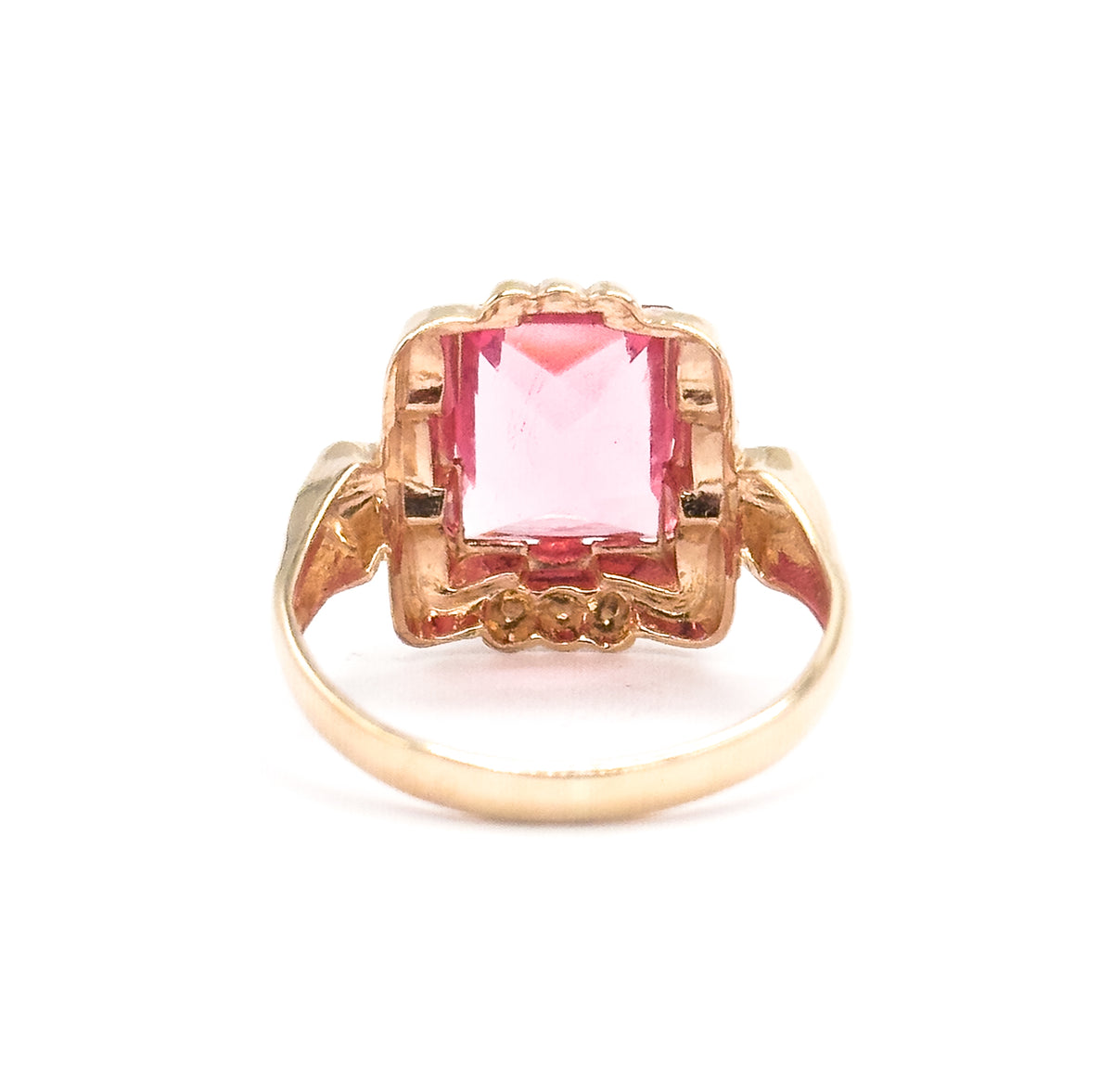 Standing with the shank arching below, the setting is seen from behind and slightly above, the pink glass glowing through the open scalloped frame with beaded accents at its top and base.