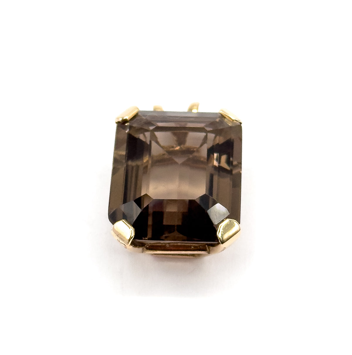 Tipped forward onto its face, the smoky quartz fills the frame with the two lower yellow gold prongs raised toward the viewer and only the tips of the upper prongs and bail peeking over the top edge.