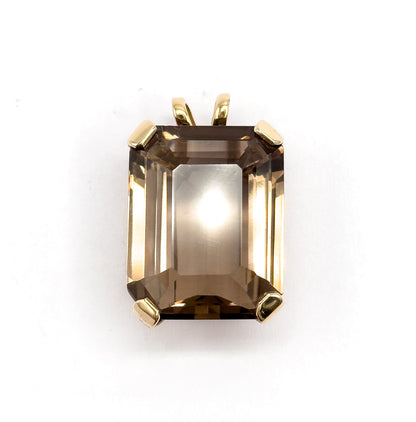 Square-on from the front, the golden brown emerald-cut quartz is centred with a bright highlight at its table, the split yellow gold bail standing clear above the four prongs.