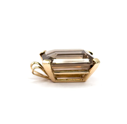 A low side-on view at eye level, the quartz lying on its side so the yellow gold gallery rail and the looped bail at the left stand out in profile.