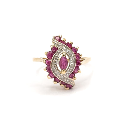 Straight-on view of the full face, showing the marquise ruby cradled between two diamond-set white gold waves inside the oval of sixteen round rubies, with the yellow gold shank behind.