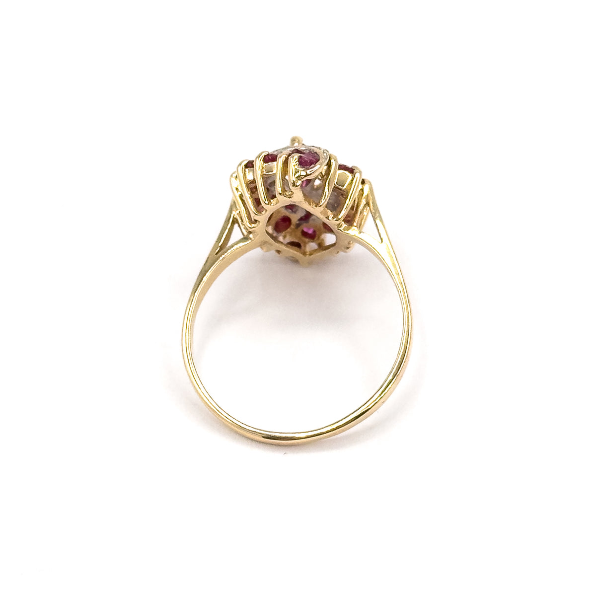 Standing upright on a white background, seen from behind so the open gallery, split shoulders and the full round of the slender yellow gold shank are visible beneath the ruby-set head.