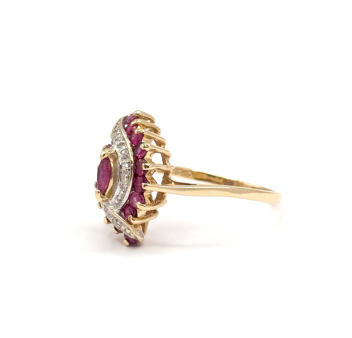 Near-profile from the right, the ruby-set head turned away so a row of raised prong tips stands up like a comb above the white gold border, the marquise ruby just visible at the left edge.