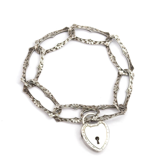 Seen from directly above as a closed oval circle, every elongated link's fan-shaped floral engraving is visible in turn, with the heart-shaped lock clasp hanging at the bottom edge.