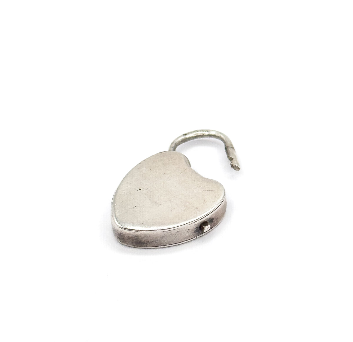 Close-up of the heart-shaped lock on its own, shackle swung open above the plain smooth face, with a small pin visible in the banded rim along the lower edge.