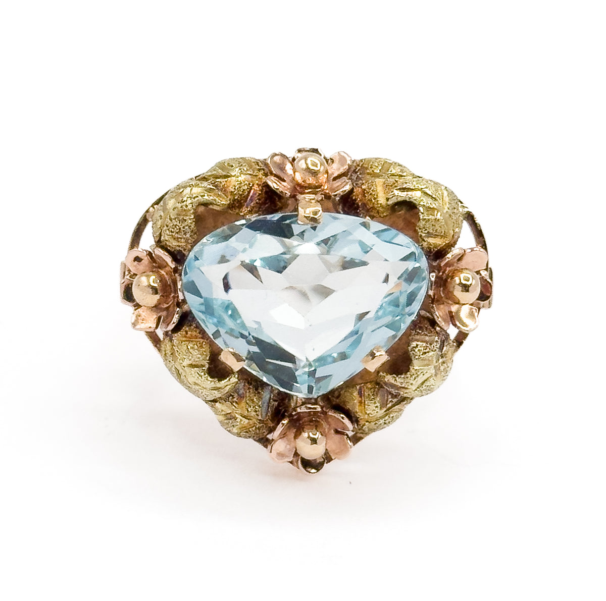 Close overhead crop on the face, filling the frame so the aquamarine's broad triangular facets and the four rose gold flowers between green gold leaves read in fine detail.