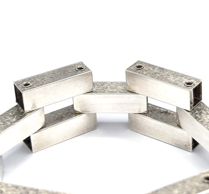 Looking down into the standing circle from above, the flat polished tops of the bars show their hinge pin heads while the open bar ends reveal the hollow interiors of each gate link.
