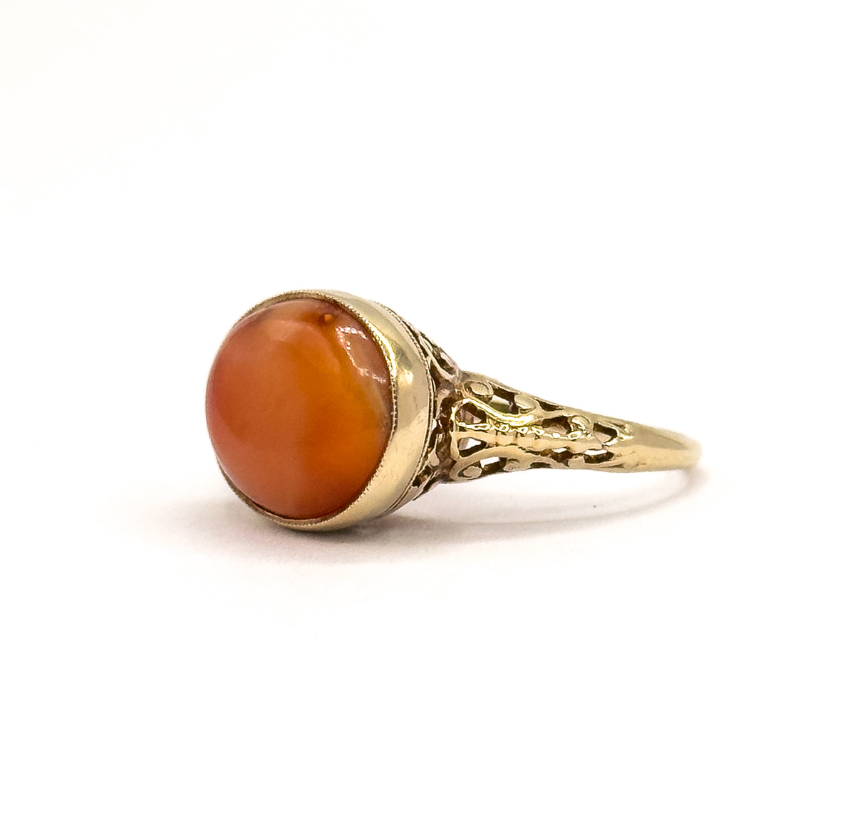 Almost the same view with slightly different angle, the coral cabochon turned to show its paler banded areas while the milgrain bezel and pierced filigree shoulder taper away to the shank.