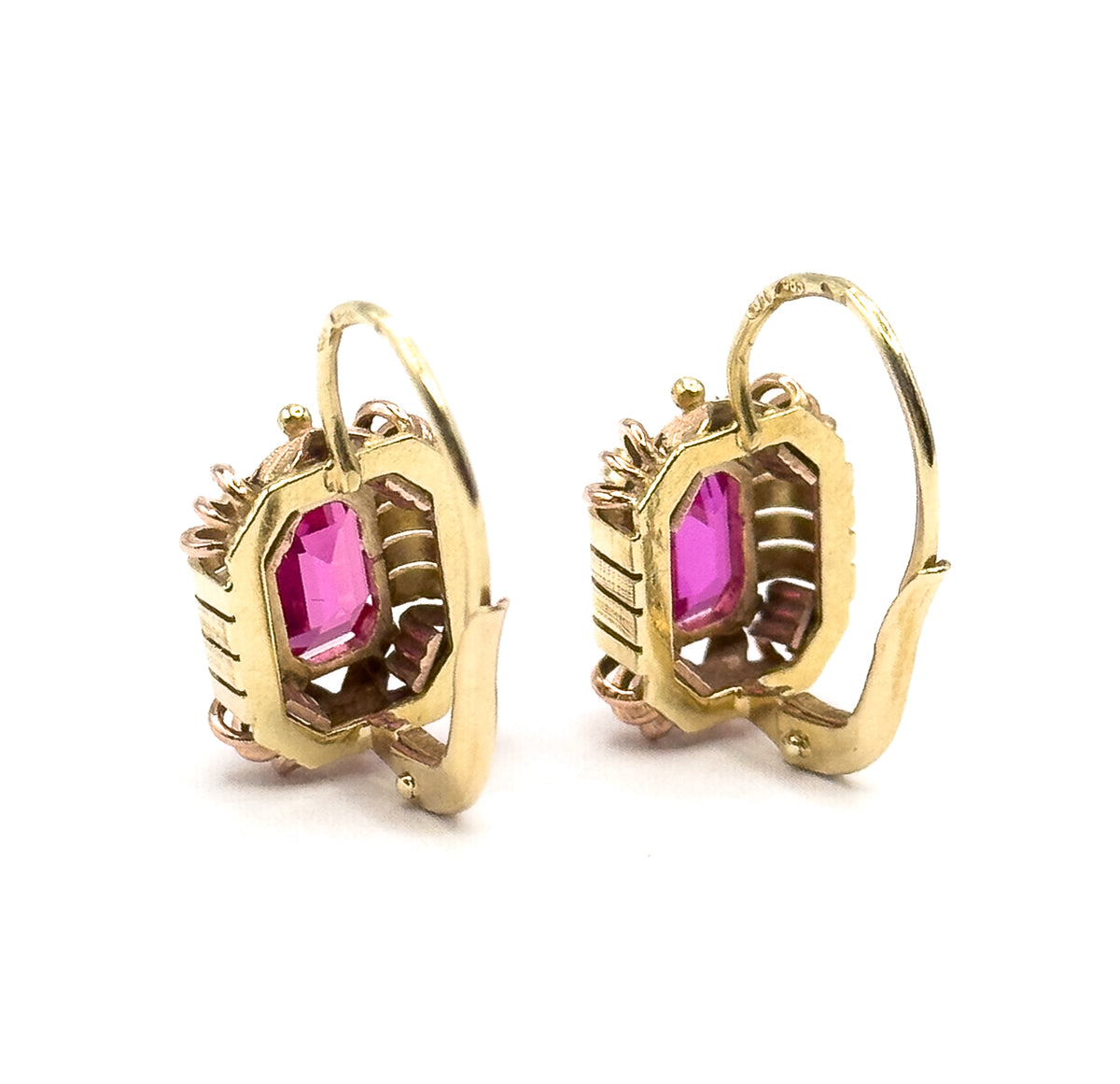 Both earrings seen from the side and slightly behind, showing the open gallery backs of the bezels, the ribbed frame edges and the long curved hook wires swinging out behind.