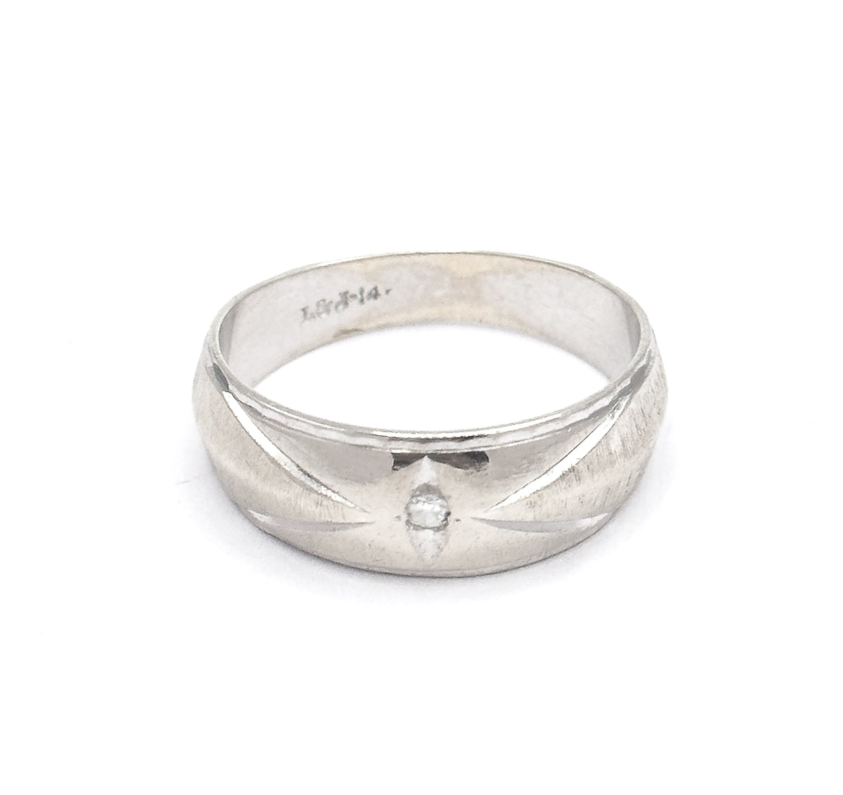 Standing upright with the hoop's opening tilted toward the viewer, the stamped marks inside the shank are legible above the wide front face and its centred diamond in the incised star.
