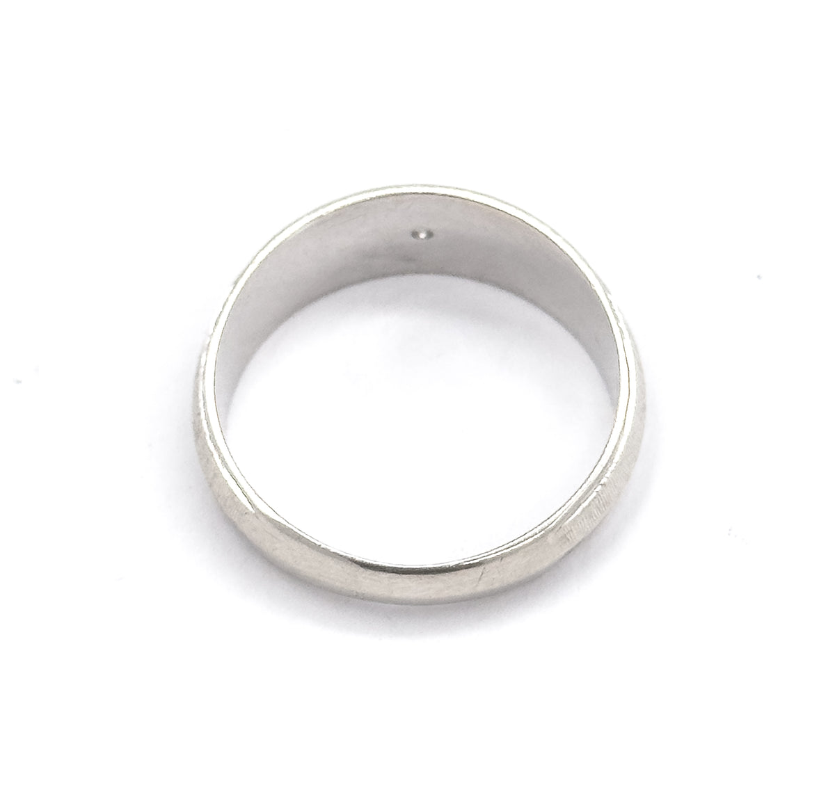 Viewed from above through the open band so the smooth interior and the tip of the small diamond showing inside the setting are visible, the wide face thinning to the narrow shank.