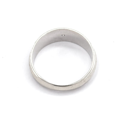 Viewed from above through the open band so the smooth interior and the tip of the small diamond showing inside the setting are visible, the wide face thinning to the narrow shank.