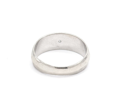 Tilted to show the plain underside of the band from behind, the smooth outer surface uninterrupted here while the small point of the diamond is just visible inside the hoop.