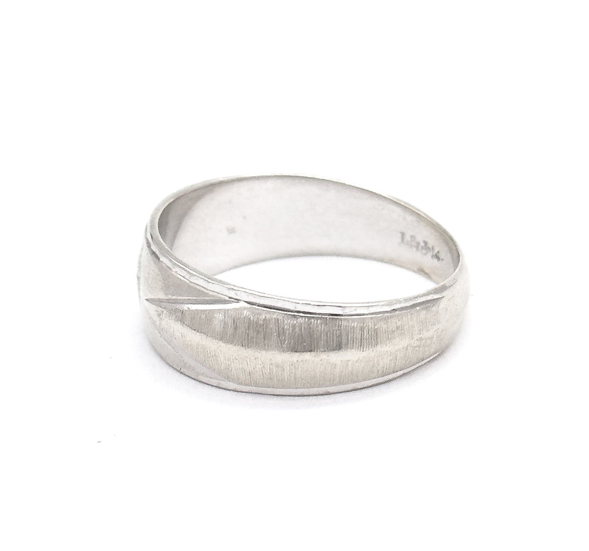 Seen from the back with the hoop tipped forward, the textured face curving away while a small maker's stamp sits inside the shank, the narrow rear of the band resting toward the viewer.