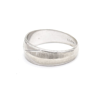 Seen from the back with the hoop tipped forward, the textured face curving away while a small maker's stamp sits inside the shank, the narrow rear of the band resting toward the viewer.