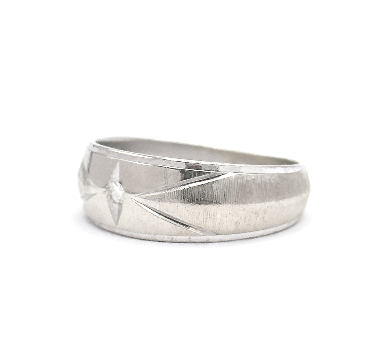 Upright front view with the wide face toward the viewer, the small diamond set within an incised star burst at the centre, diagonal engraved lines flanking it across the brushed white metal.