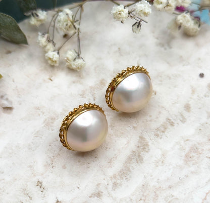 Almost the same view with slightly different angle, cropped closer so the high domed profile of each pearl and the scalloped rope twist edging around the bezels fill most of the frame.