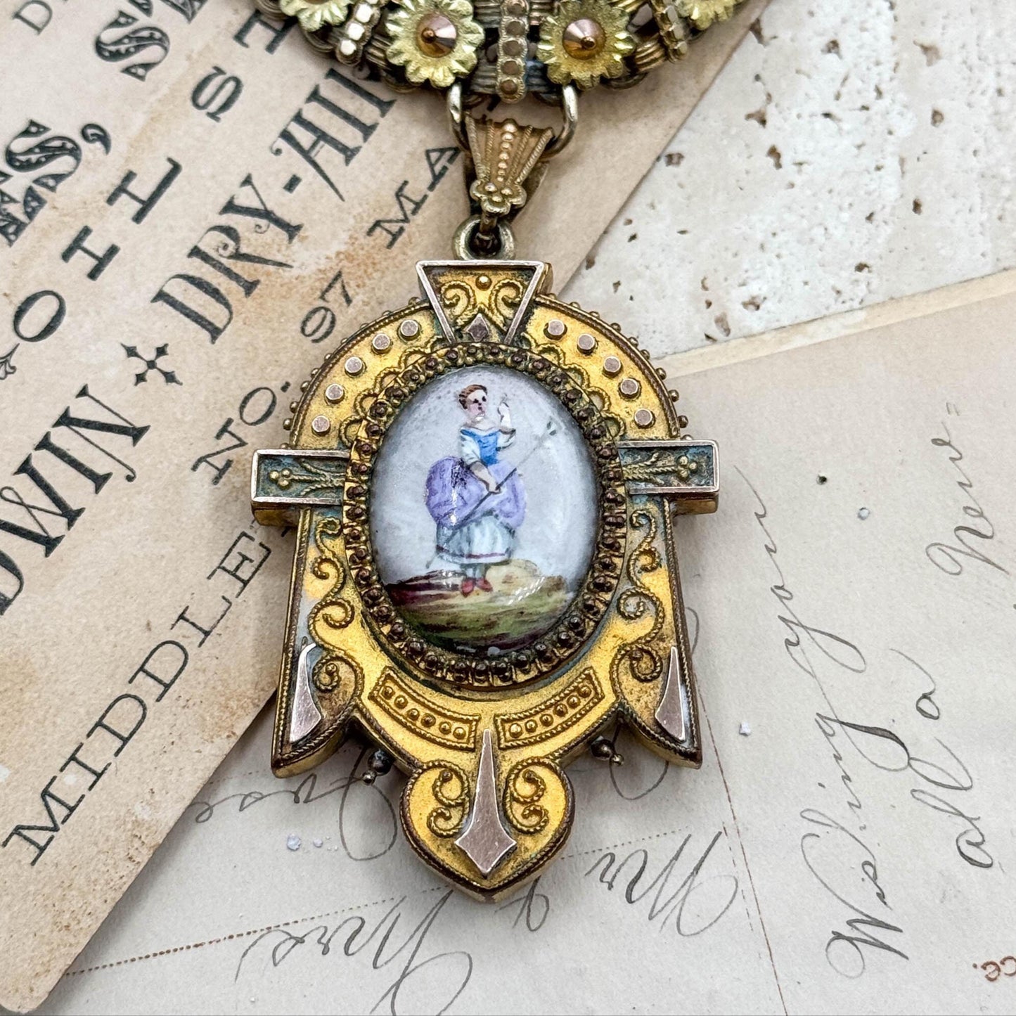 Decorative necklace with a pendant featuring a small painting on an old document background