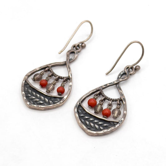 Pair of silver earrings with red beads on a white background