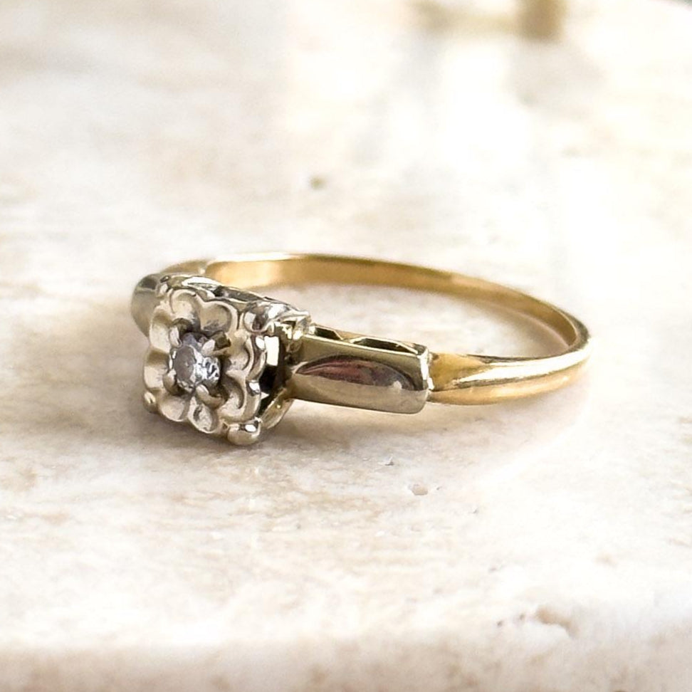 Gold ring with a diamond on a marble surface