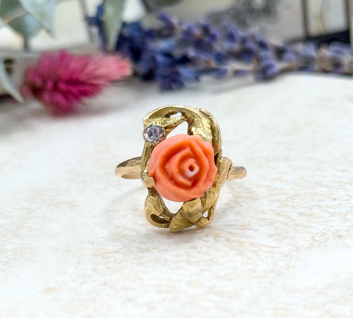 Almost the same view with slightly different angle, closer and more face-on, so the carved petals of the coral rose, the small bezel-set diamond and the open gold gallery fill the frame.