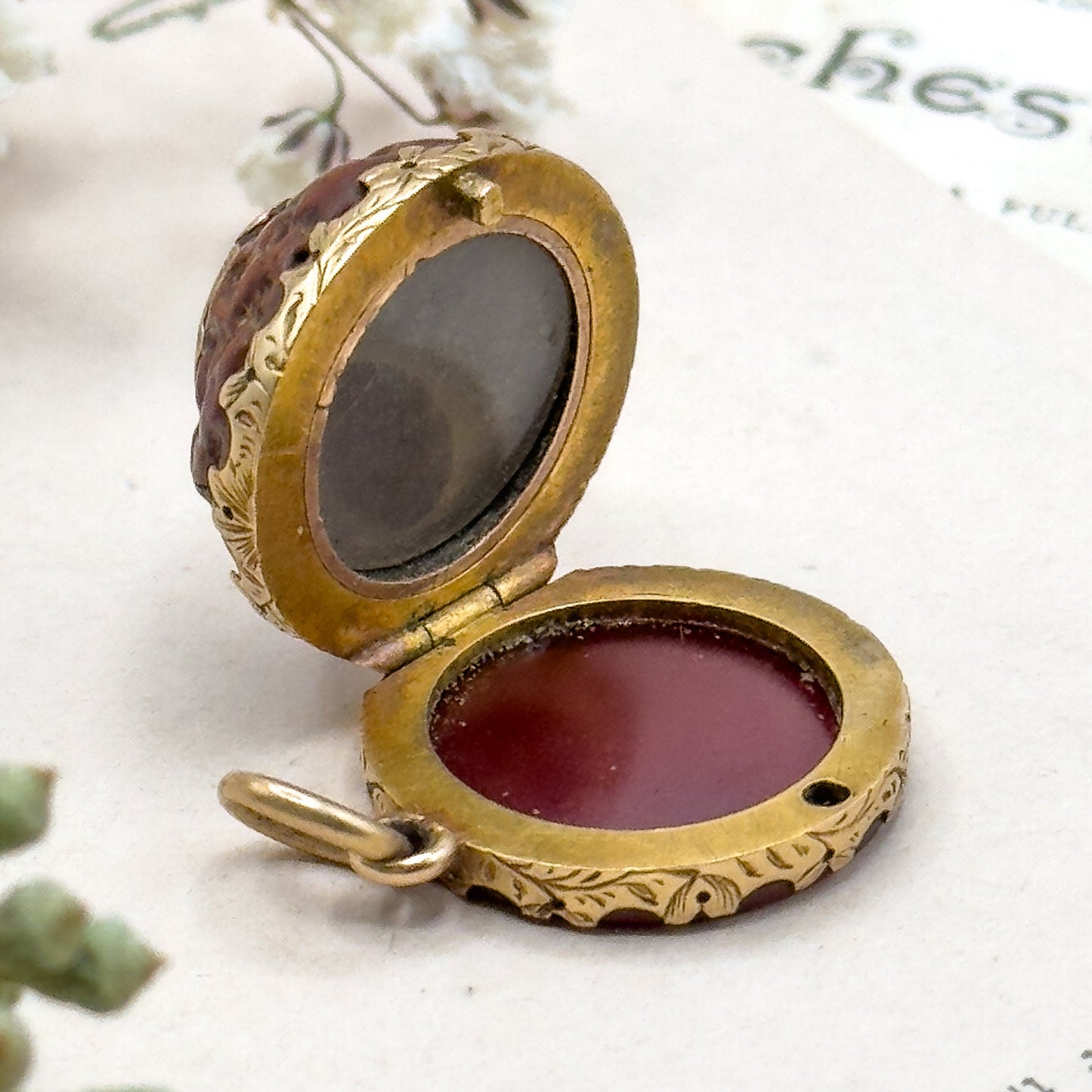 Vintage-style gold locket with a glass cover on a white surface with text.