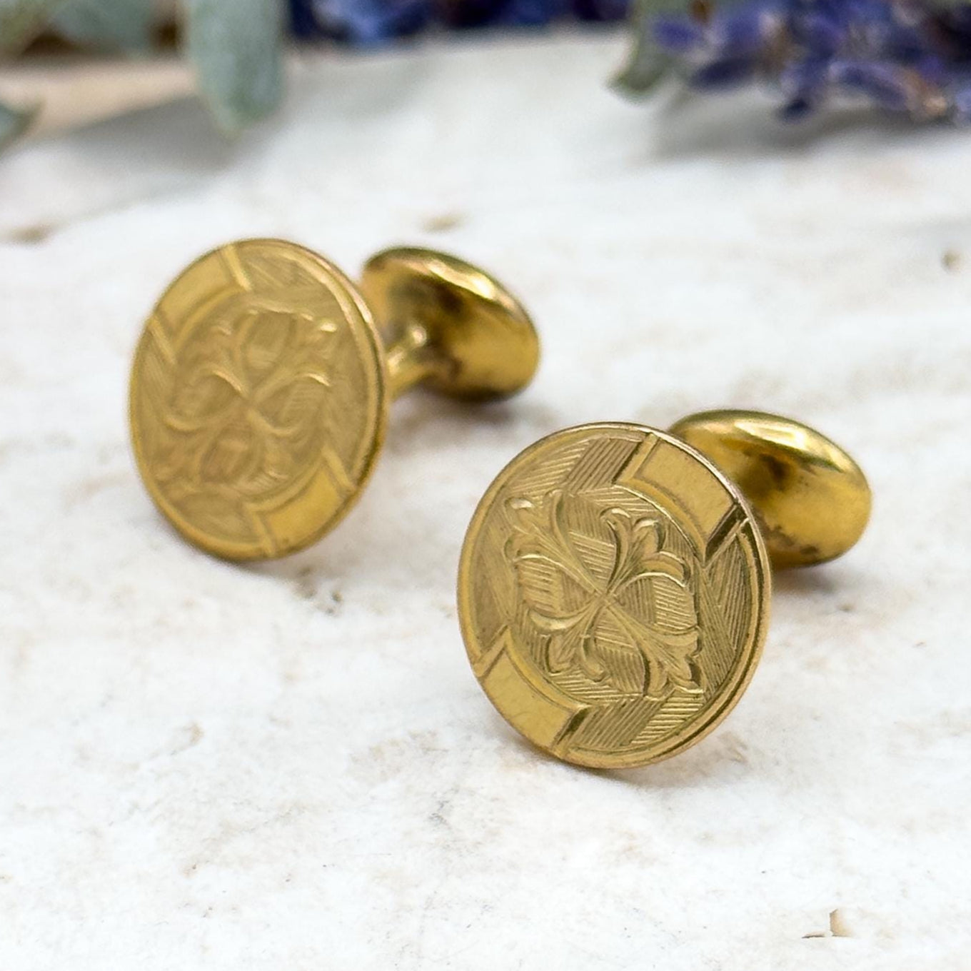 Gold cufflinks with intricate design on a light surface