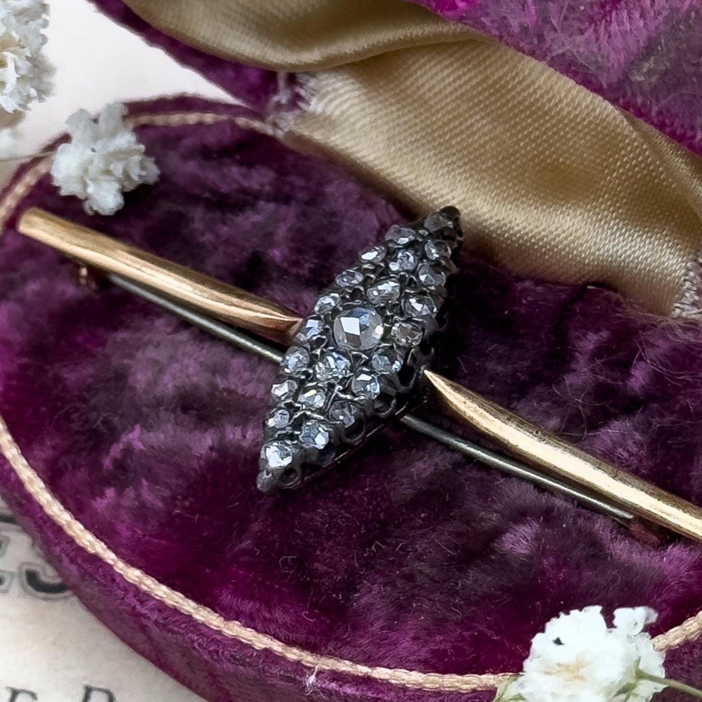 Gold brooch with gemstones in a purple jewelry box