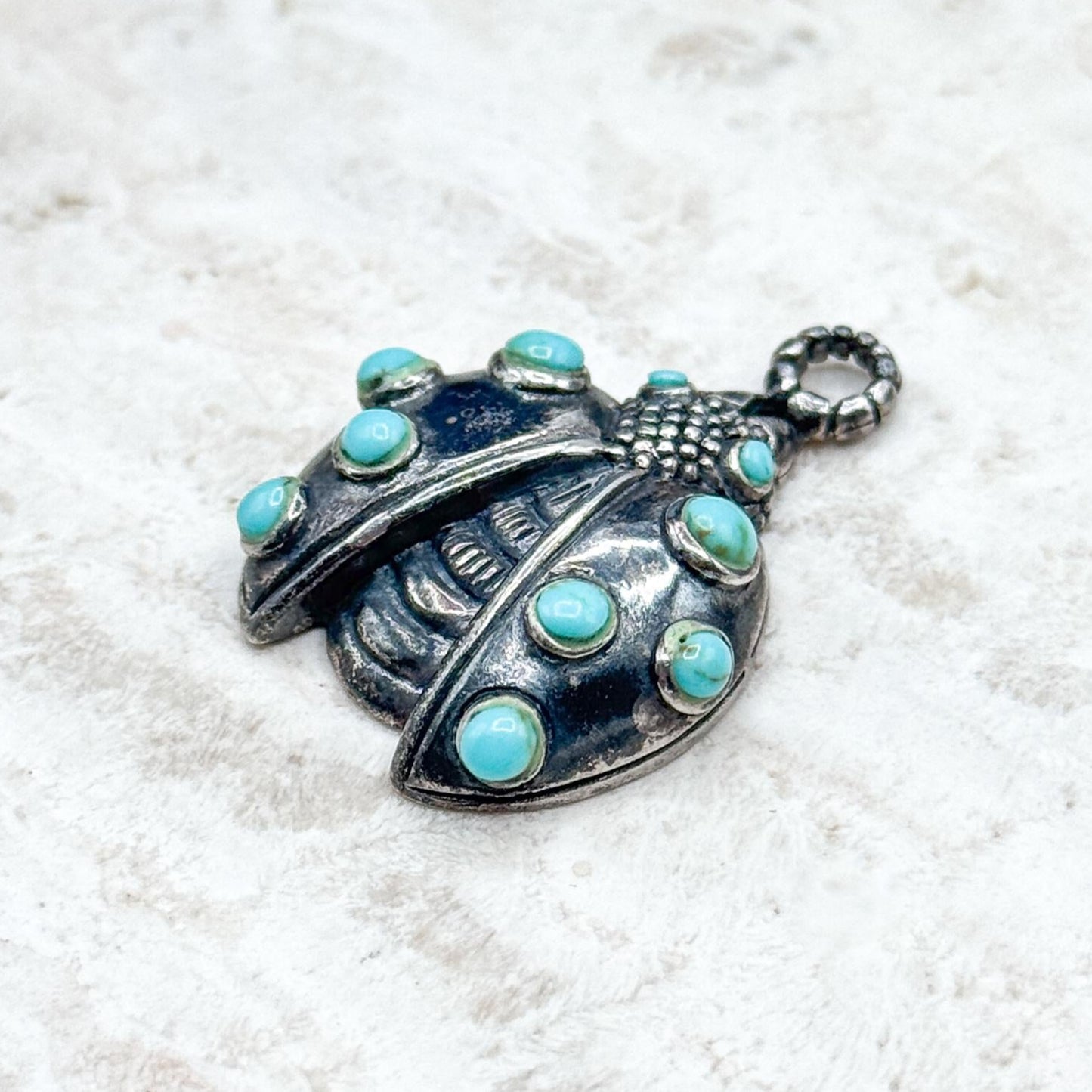 Silver pendant with turquoise stones on a white background
