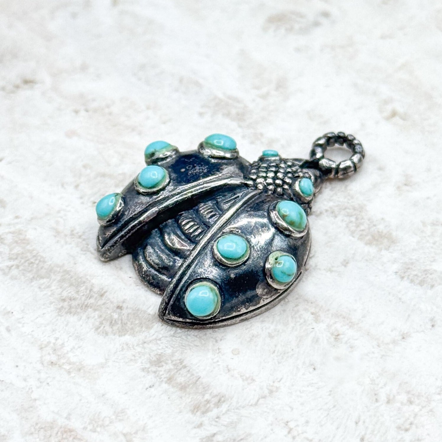 Silver pendant with turquoise stones on a white background