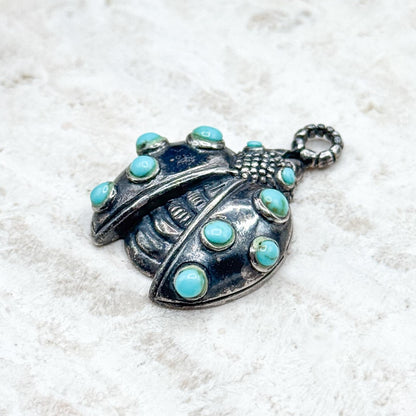 Silver pendant with turquoise stones on a white background
