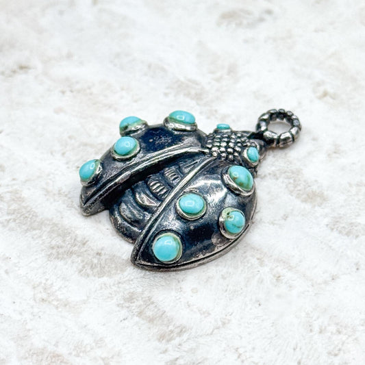 Silver pendant with turquoise stones on a white background