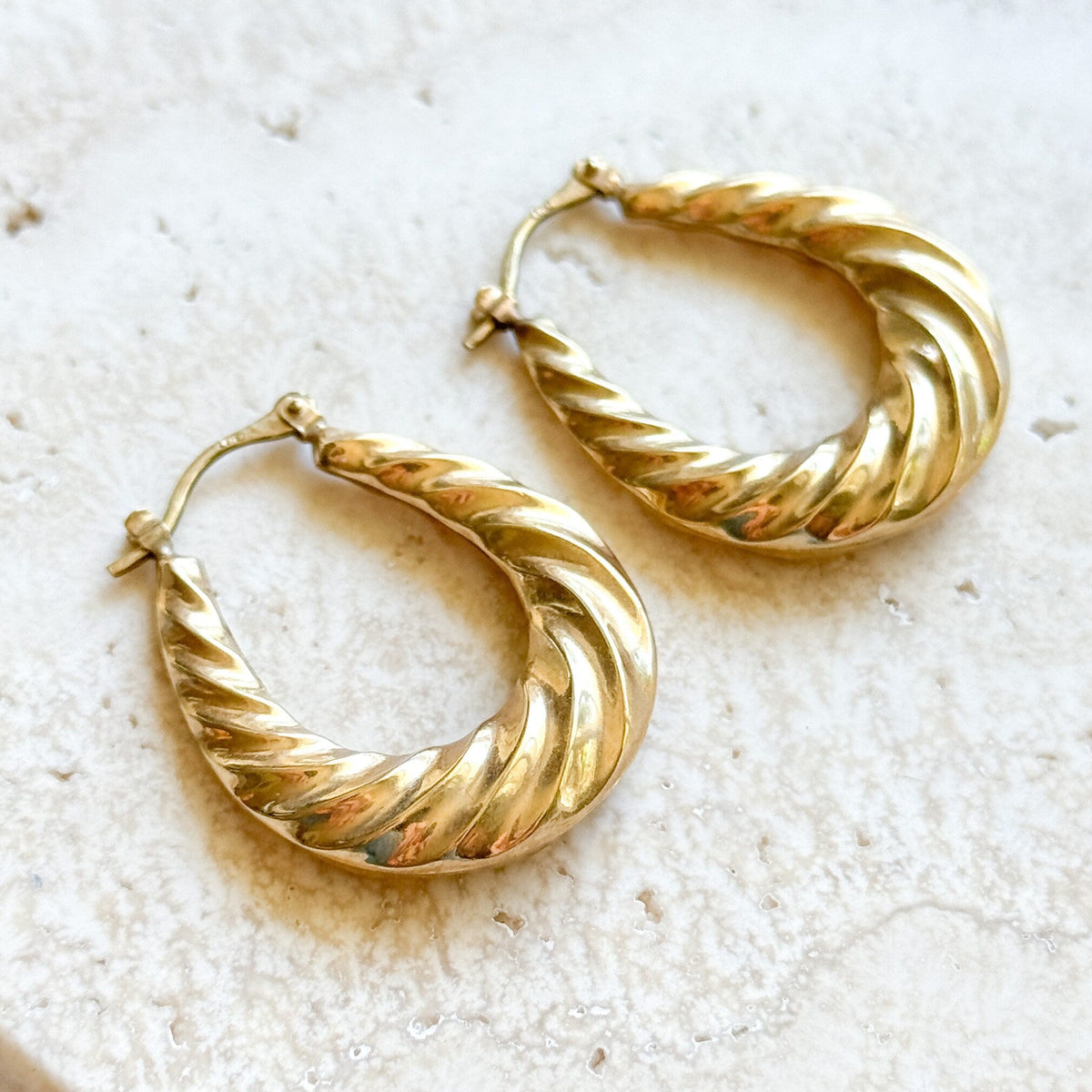 Gold hoop earrings on a textured white surface