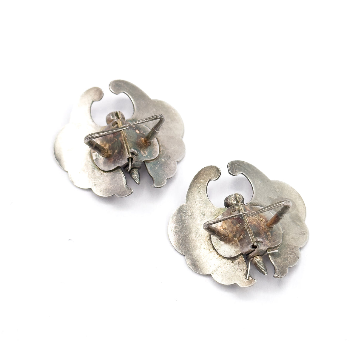 The reverse of both butterfly pins on a white background, showing the plain backs of the wings and the leg-shaped clip mechanisms with their pointed ends across each body.